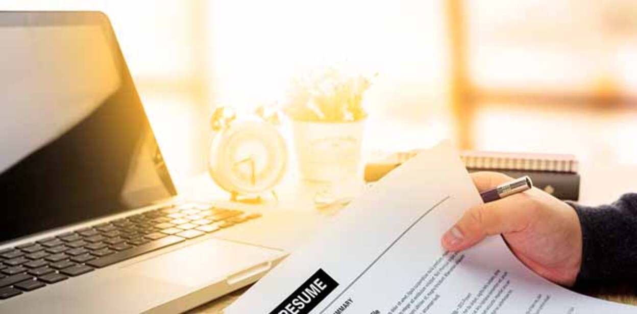 Businessman or job seeker review his resume on his desk before send to finding a new job with pen, necktie, glasses and digital tablet.