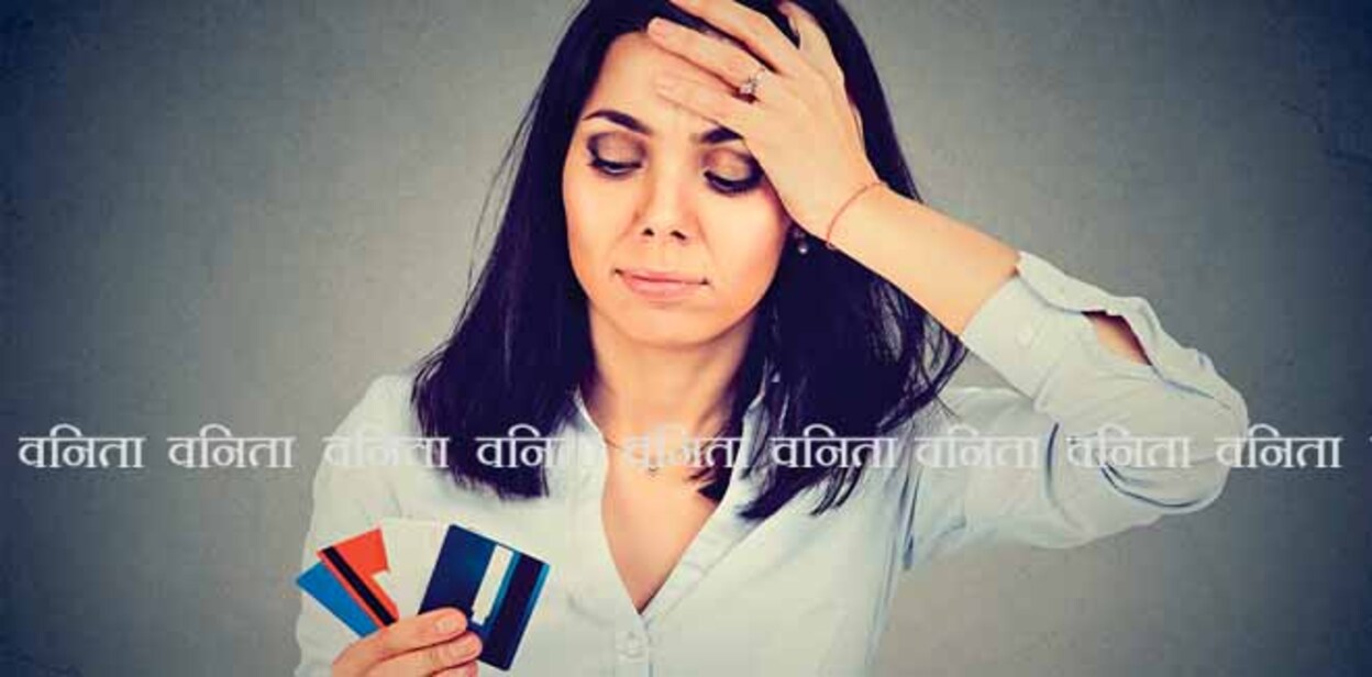 Stressed woman in debt looking at multiple credit cards isolated on gray background 