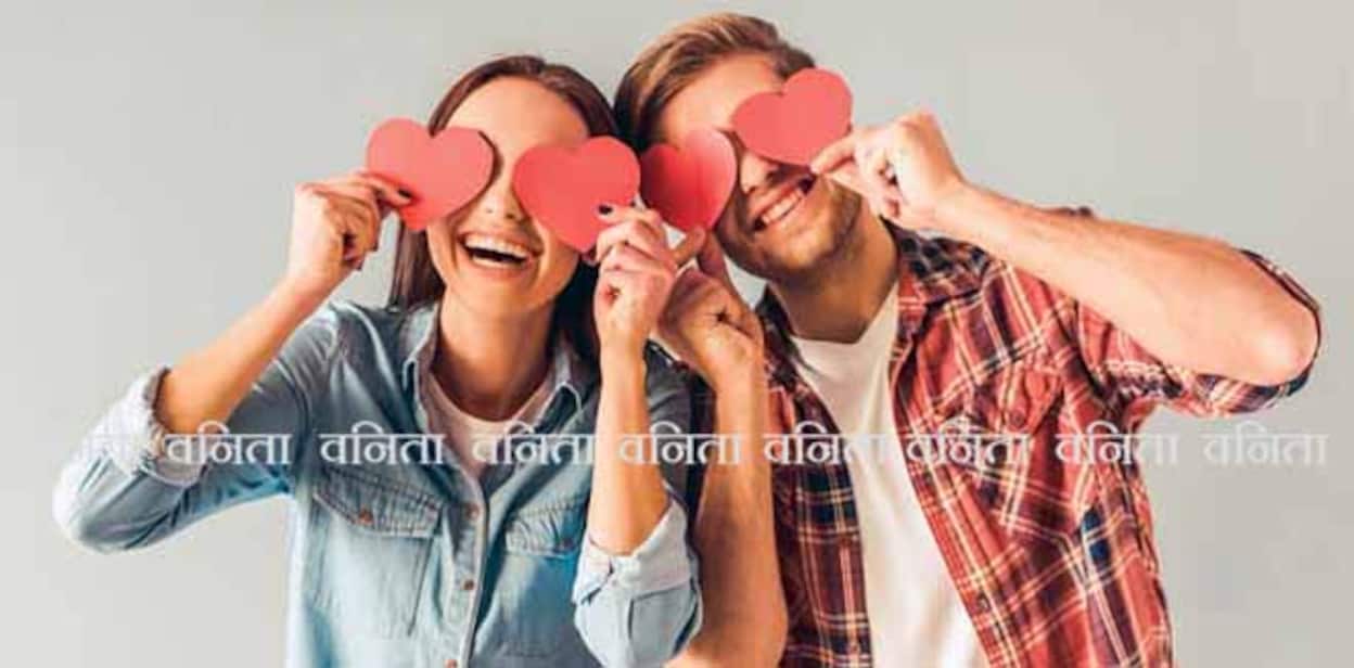 Happy young couple is holding red paper hearts and smiling, on gray background