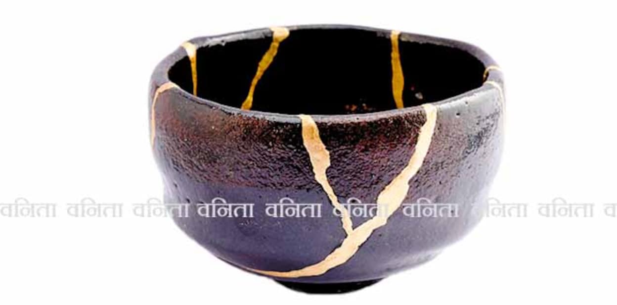 1805086438 Kintsugi black raku chawan bowl. Gold cracks restoration on old Japanese pottery restored with the antique restoration technique.The unique beauty of imperfections.