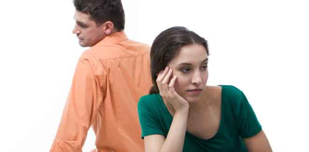 Sad woman sitting aback to boyfriend and touching her face