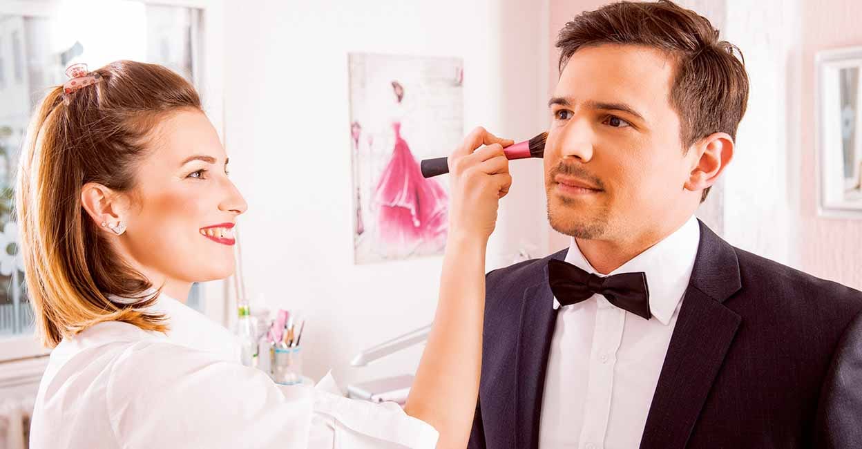 Professional Make-up artist doing young man makeup in studio