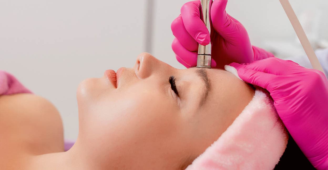 The cosmetologist makes the procedure Microdermabrasion of the facial skin of a beautiful, young woman in a beauty salon.Cosmetology and professional skin care