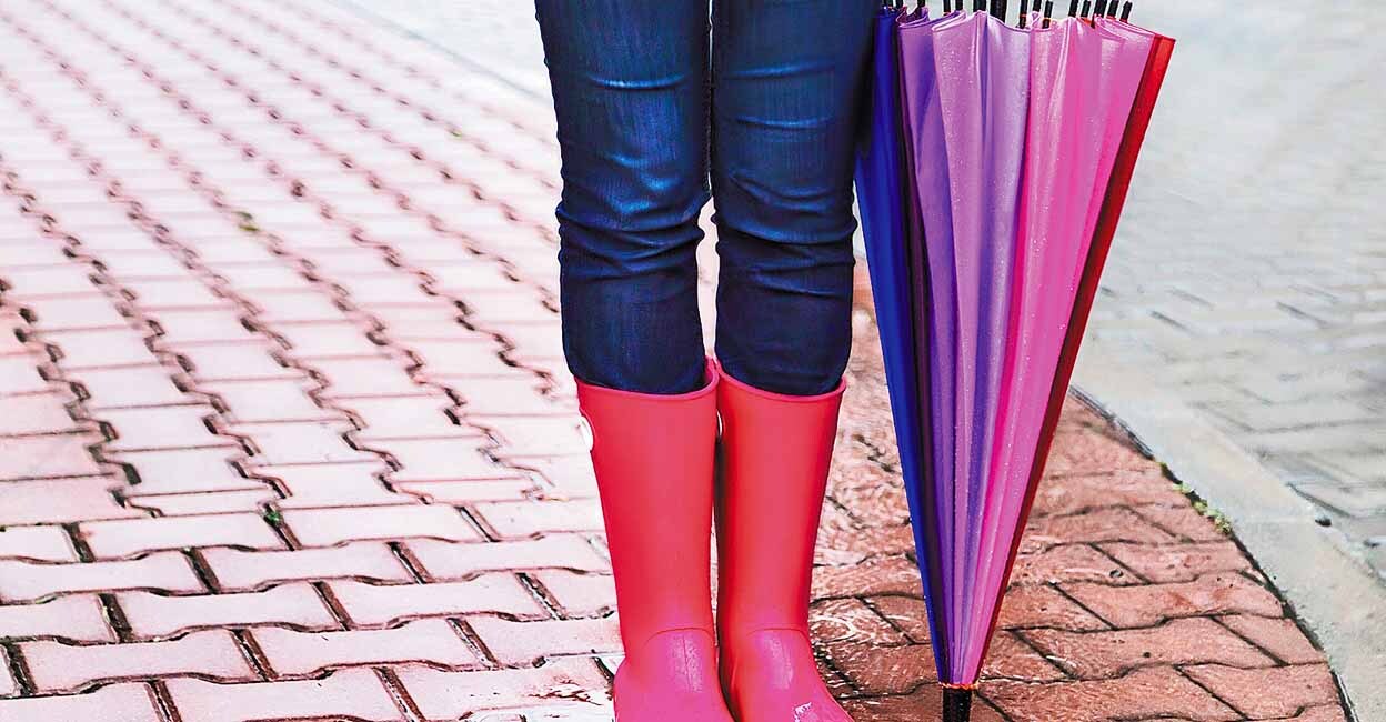 Autumn. Protection in the rain. Woman (girl) wearing pink rubber boots and has colorful  umbrella. Street, city. Raindrops. Copy space. Place for message. Concept about activity, leisure, travel.