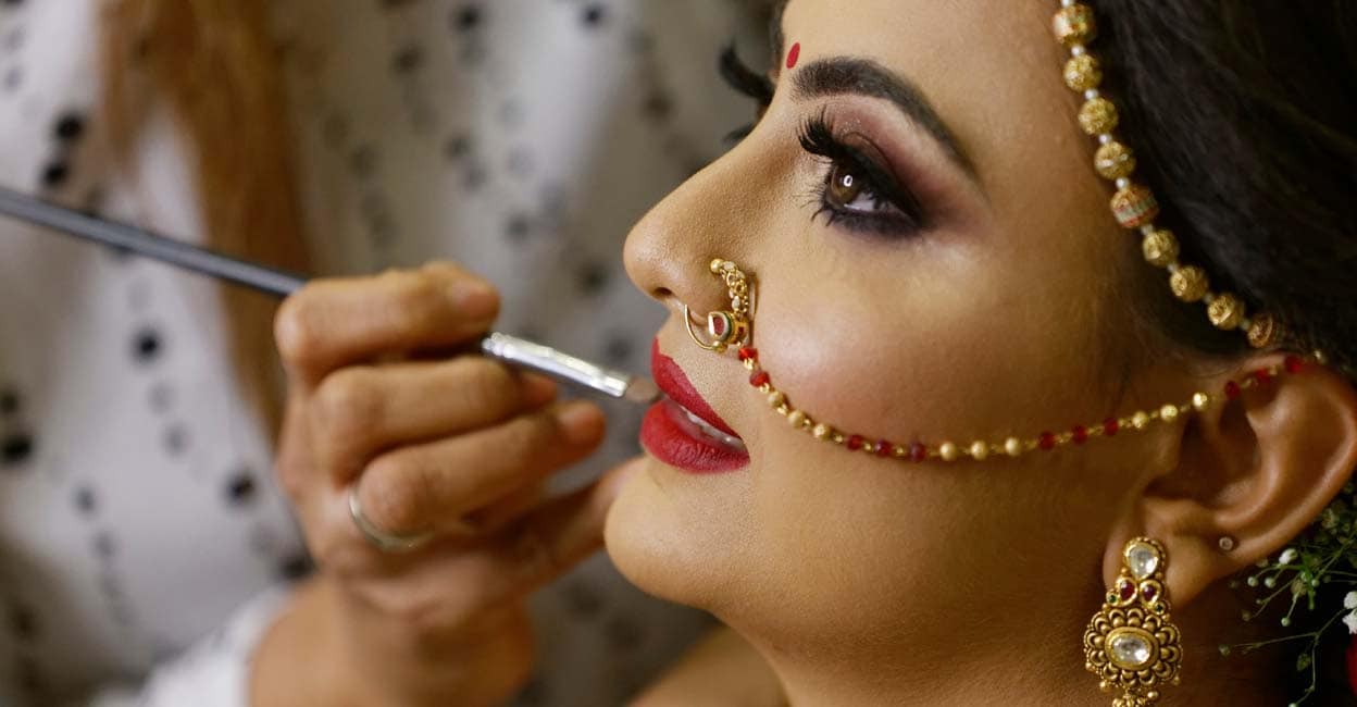 Mumbai Maharashtra India July 06 2019 unidentified wedding makeup artist making a makeup for bride Beautiful Indian gujarati bride getting ready Close-up of face Bridal makeup