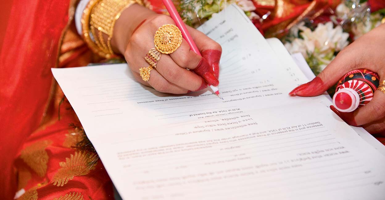 Bride doing signature on marriage register in India,