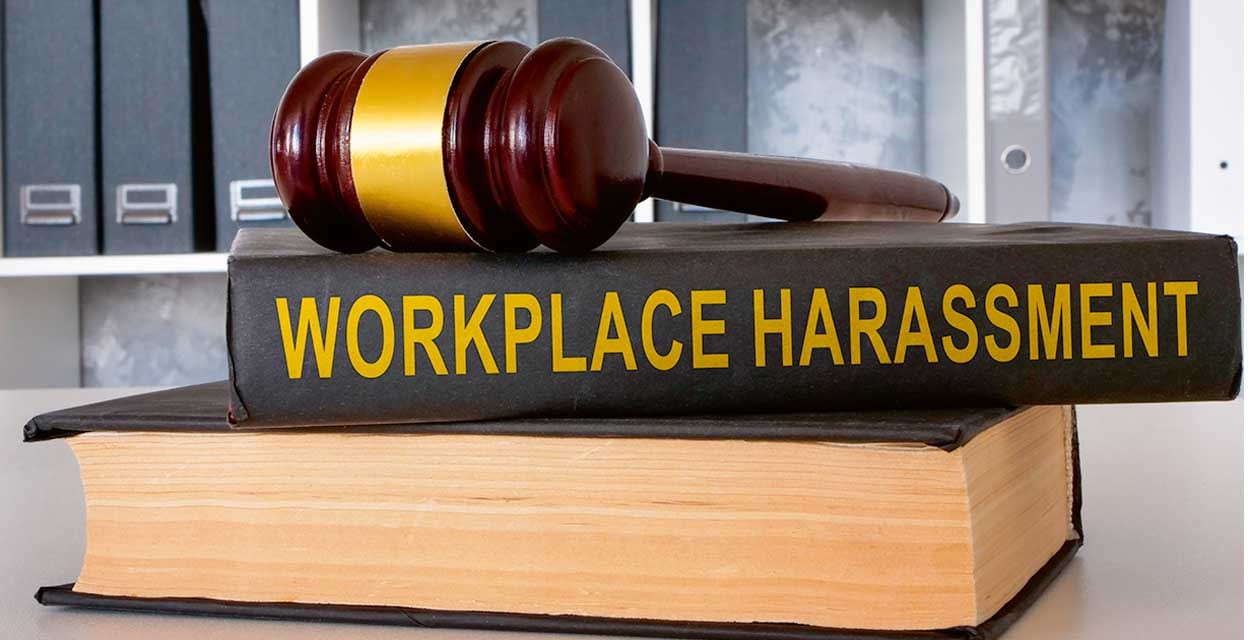 A book Workplace harassment with gavel lies on the office table.